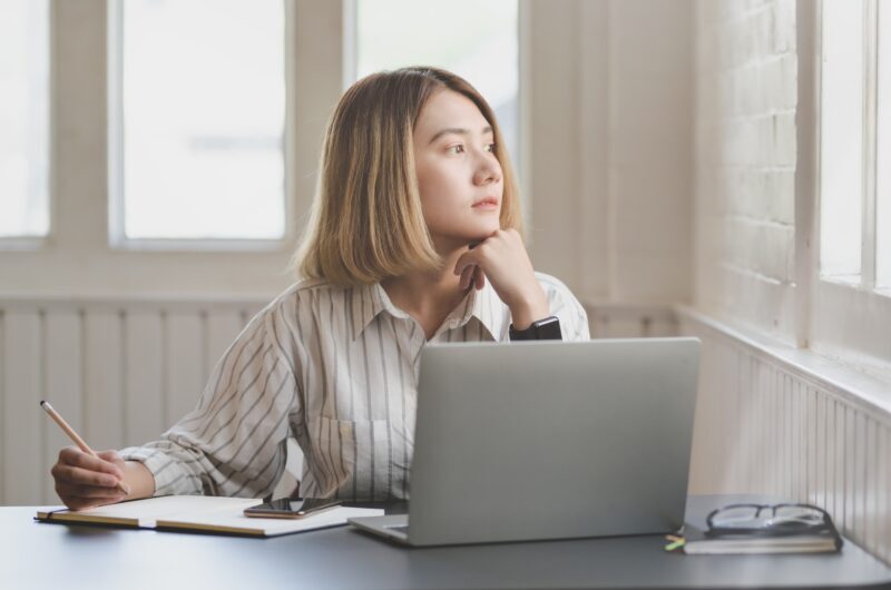 mulher reflexiva enquanto trabalha olhando para a janela